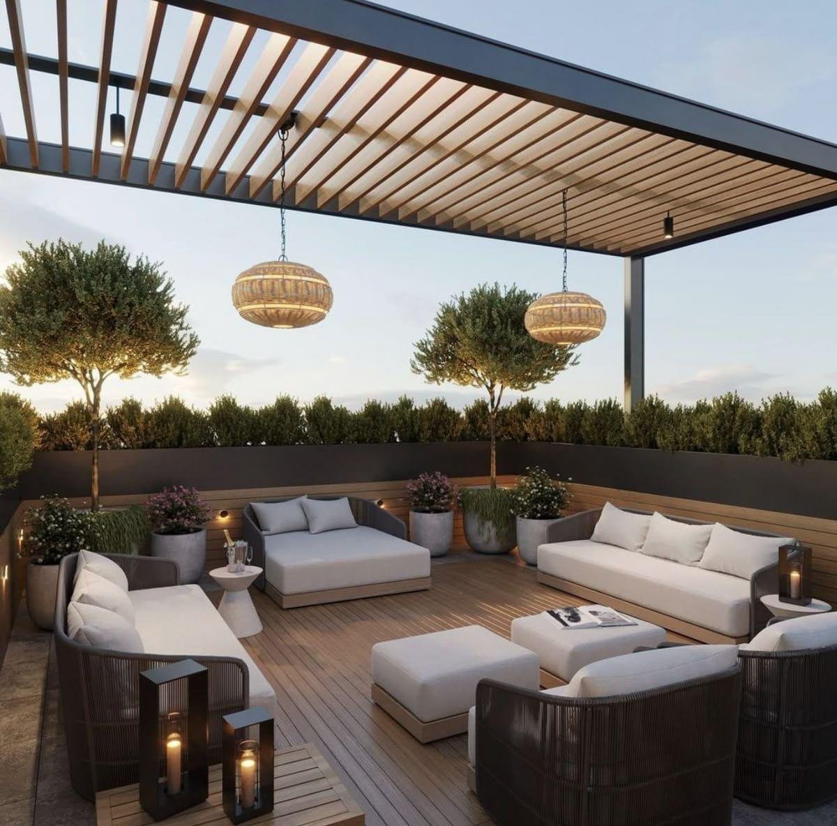 Outdoor rooftop patio with modern seating, potted plants, trees, hanging wicker lights, and a wooden deck.